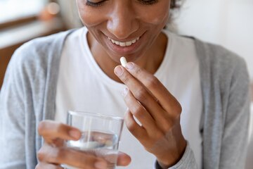 Woman taking capsules with water as part of her nightly routine