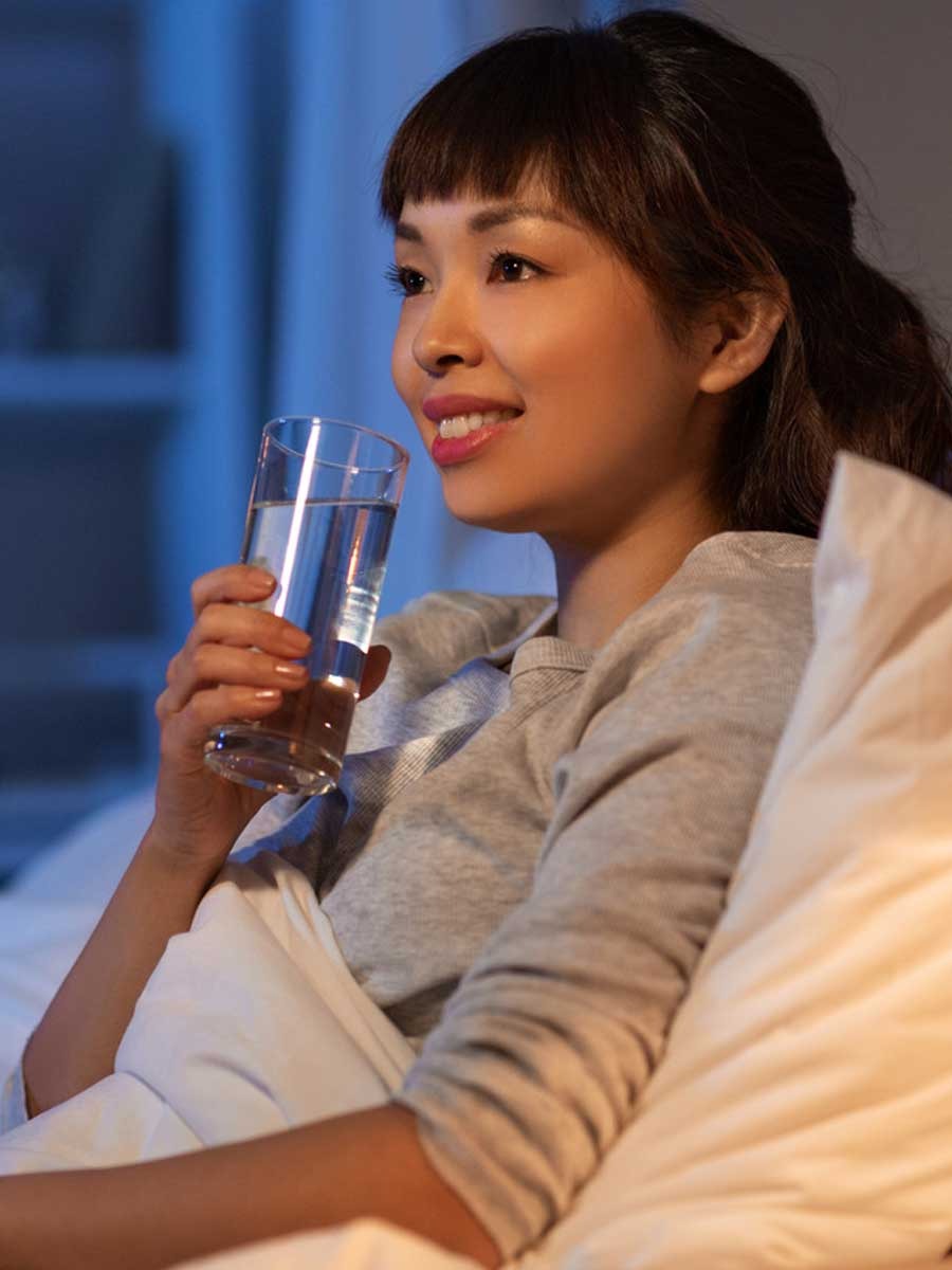 Woman relaxing with a glass of water before bed